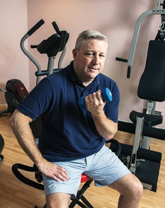 picture of Gary Silverman curling weights while seated in a gym