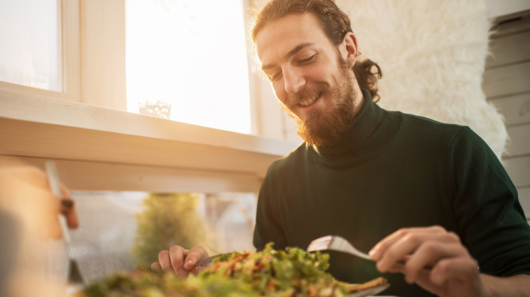 desktop-GettyImages-507686834-young-man-eating-salad-healthy-meal-smiling-sweater-fall-spring-winter