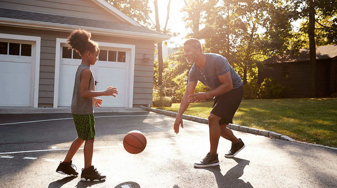 desktop-GettyImages-904506166-Father-And-Son-Playing-Basketball-On-Driveway-At-Home