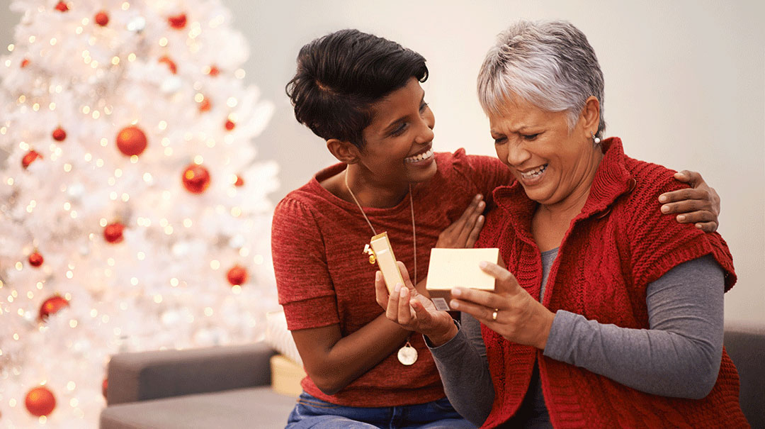 desktop_woman-giving-gift-to-senior-mother-at-Christmas-smiling-hugging_GettyImages-518682515