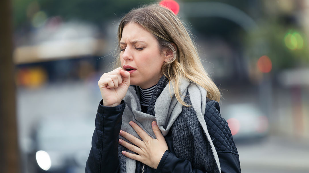 desktop_young-woman-coughs-coughing-in-the-street_GettyImages-1076823284