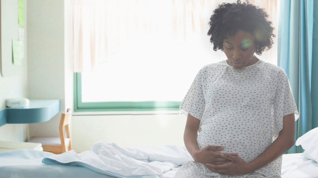 Pregnant woman holding stomach in hospital setting