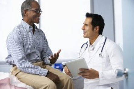 Doctor In Surgery With Male Patient Using Digital Tablet