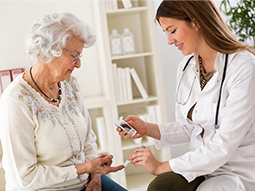 Young female doctor taking diabetes blood test of senior woman