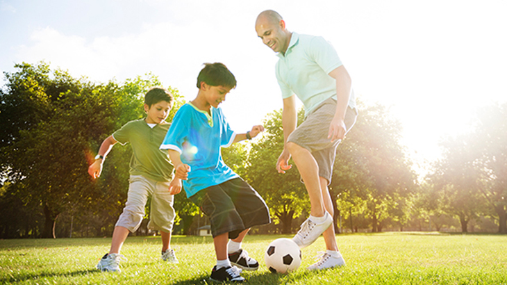 Father_playing_soccer_with_young_boys