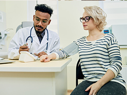 Doctor taking blood pressure of young patient