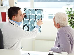 Neurosurgeon examining x-ray scans of senior patient