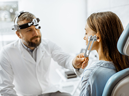 Otolaryngologist examining ears with ENT tuning fork of young patient