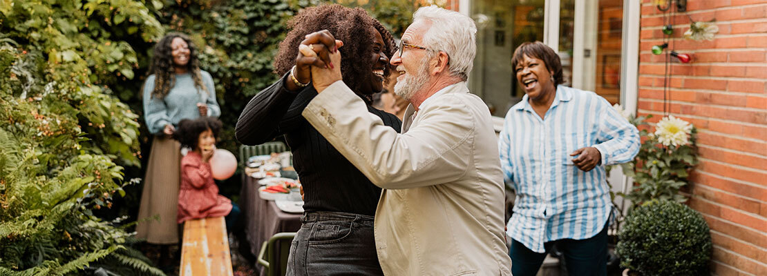 Smiling multi-ethnic senior married couple keeping active and running together on suburban street in spring